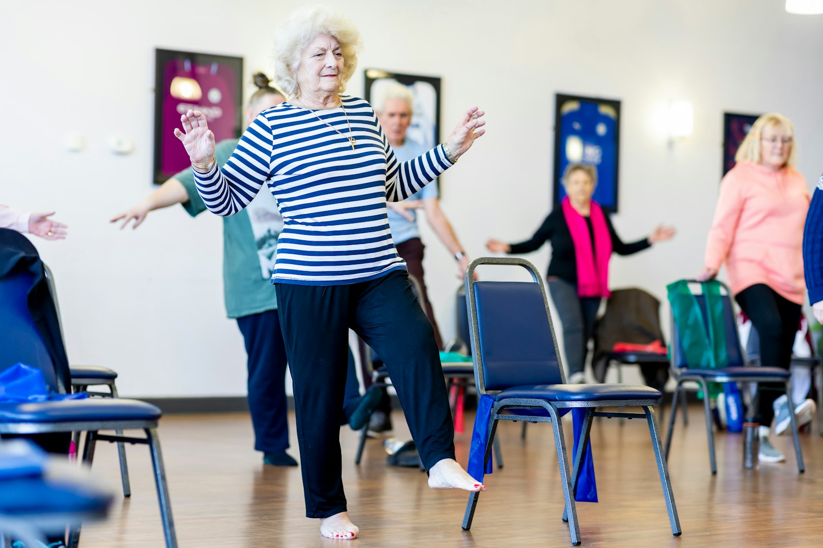 Seniors exercising on chairs in a bright studio